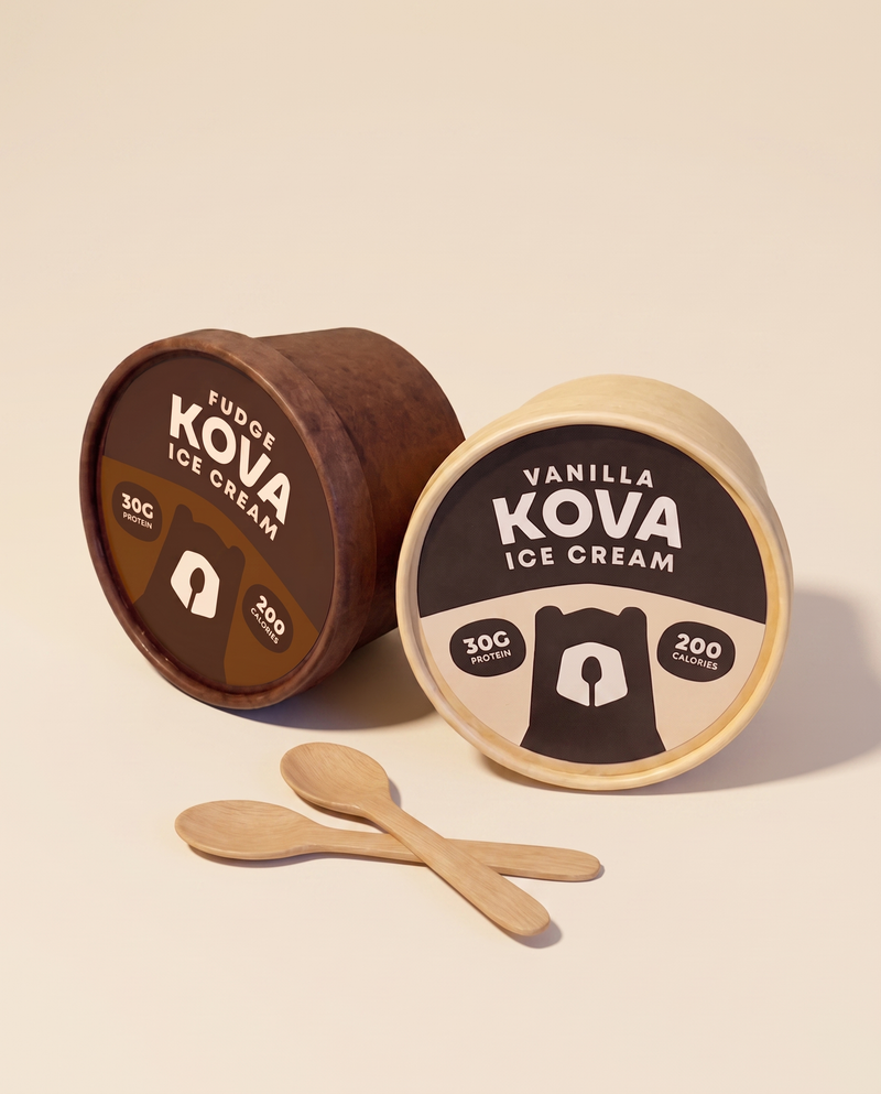 Kova fudge and vanilla protein ice cream cups with wooden spoons on a cream background