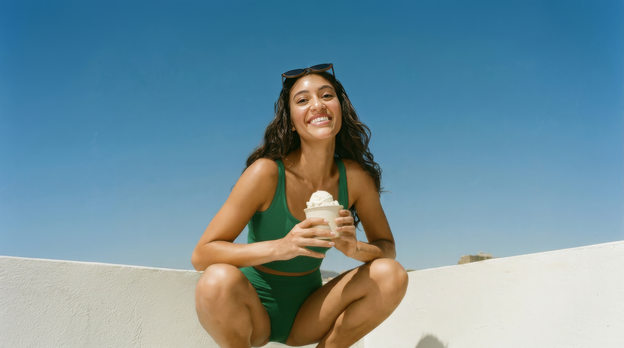 A smiling woman in the LA sun holding a cup of Kova protein ice cream