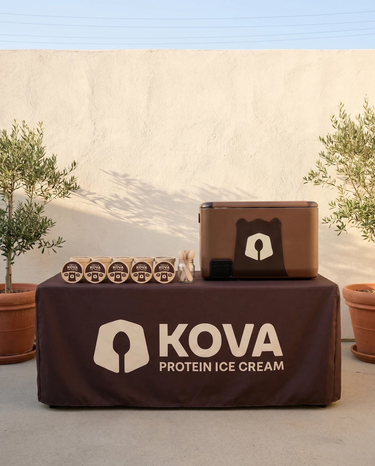 A Kova pop-up table with a cooler and a row of cups in a sunny LA courtyard
