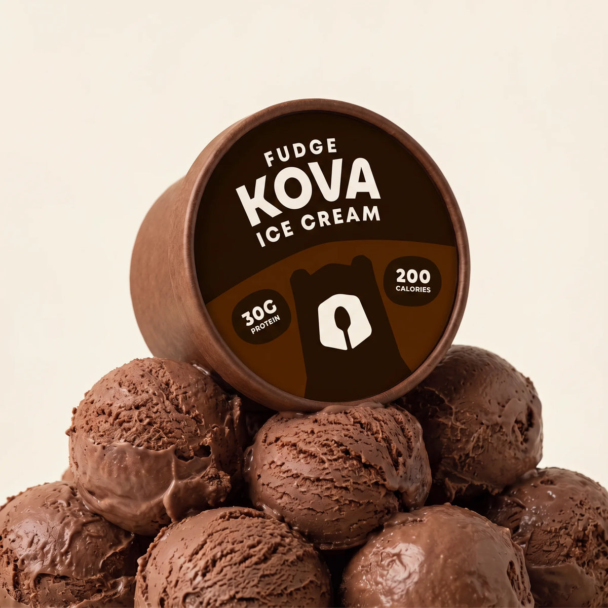 Kova Fudge protein ice cream cup resting on a mountain of chocolate fudge ice cream scoops
