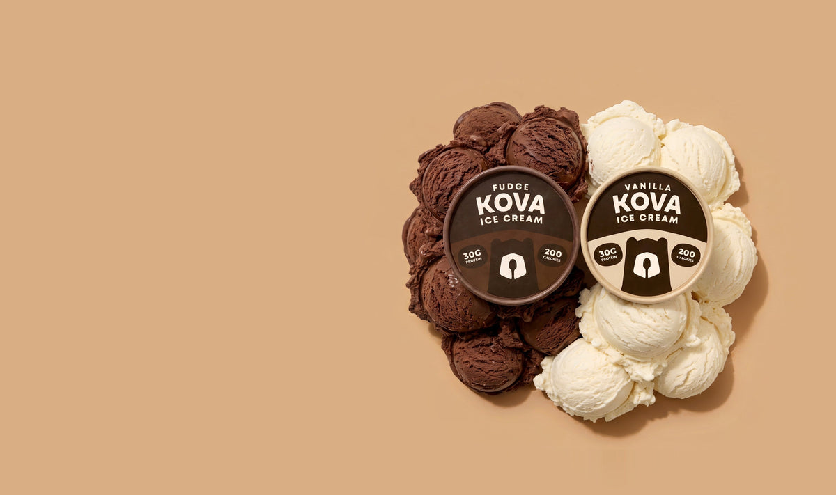 Kova fudge and vanilla cups tipped on their sides, lids facing up, in a mound of fudge and vanilla scoops