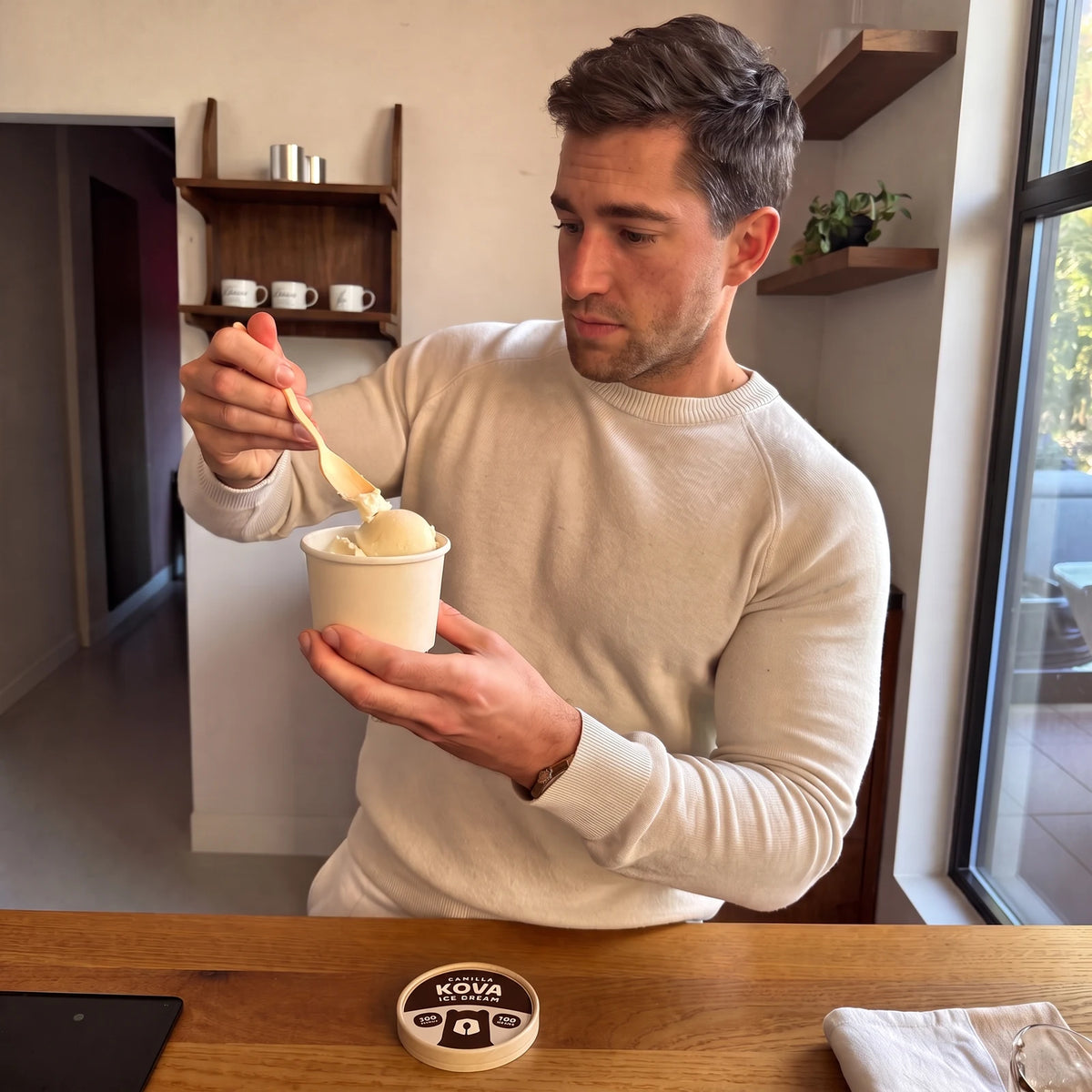 A man taking a spoonful of Kova Vanilla protein ice cream at his kitchen counter
